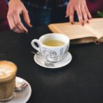 Könyvet olvasó személy teával egy asztalnál, képernyőmentes kikapcsolódás