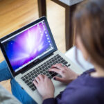 Laptopot használó személy a kanapén, fájlok kezelése a gépen