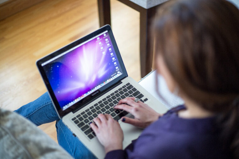Laptopot használó személy a kanapén, fájlok kezelése a gépen